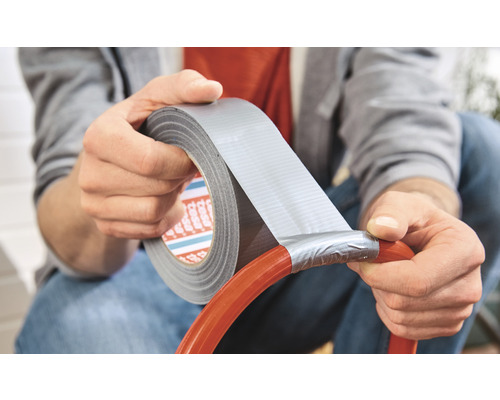 Eine Person repariert einen Gartenschlauch mit Gewebeband.