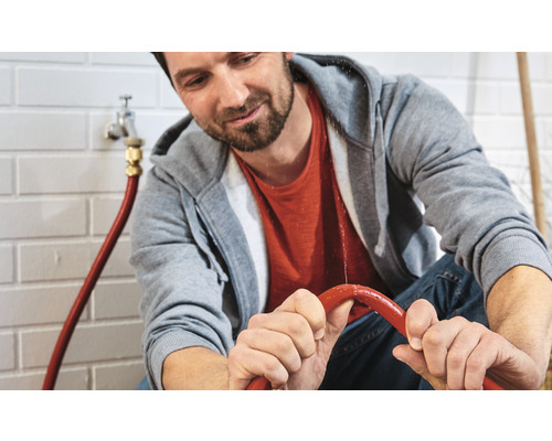 Mann repariert einen undichten Wasserschlauch.