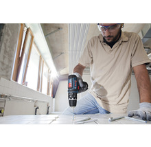 Ein Mann bohrt mit einer Bohrmaschine in Fliesen