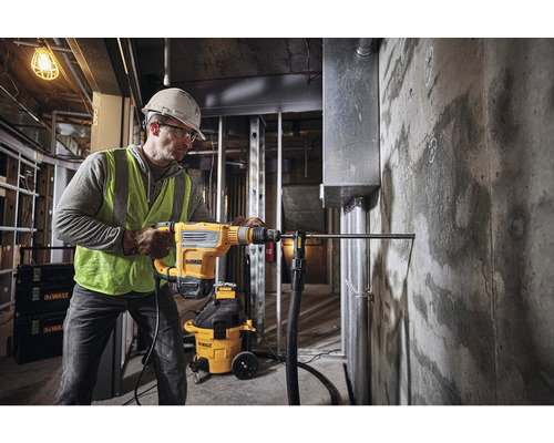 Ein Mann bohrt mit einem Bohrhammer der Marke DeWalt ein Loch in eine Betonwand.