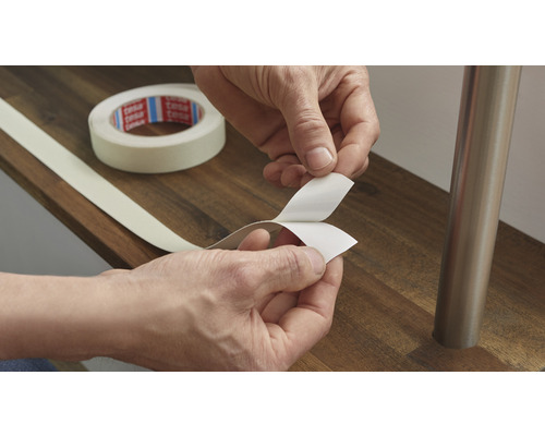 Person entfernt Schutzfolie von doppelseitigem Klebeband.