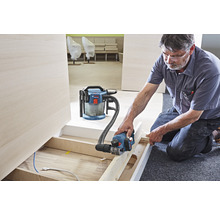 Handwerker arbeitet mit einem Elektrohobel und einem Staubsauger in einem Raum.