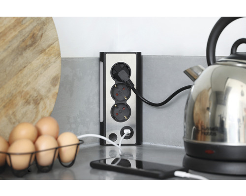 Mehrfachsteckdose mit USB-Anschluss auf einer Küchentheke mit Eiern und Wasserkocher.