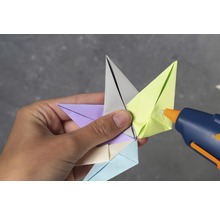 Person klebt Origami Stern mit Heißklebepistole