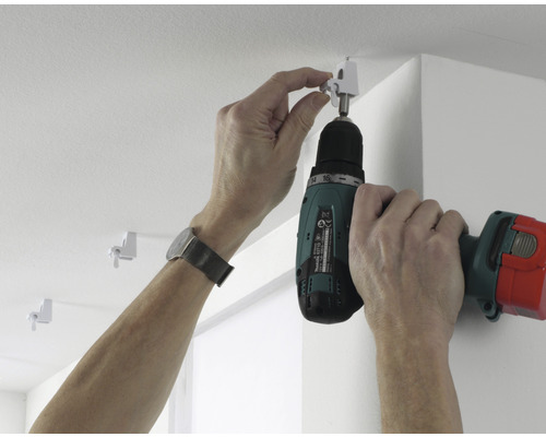 Montage einer Gardinenschiene mit einem Akkuschrauber an der Decke.