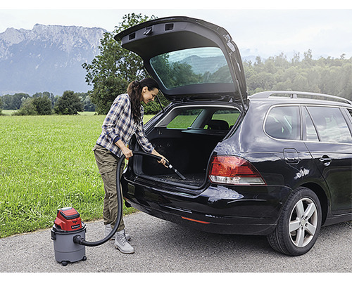 Frau saugt Kofferraum eines Autos mit einem Nass Trockensauger