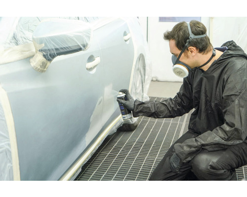 Mann lackiert Auto mit Sprühdose