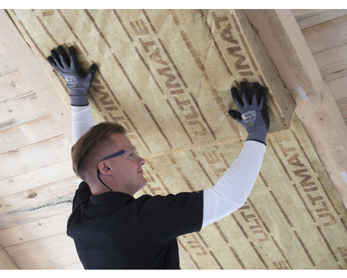 Ein Mann befestigt Dämmwolle an einer Holzdecke.