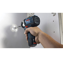 Eine Person benutzt einen Akku-Schlagschrauber, um eine Schraube in ein Objekt zu schrauben. Bosch Logo.