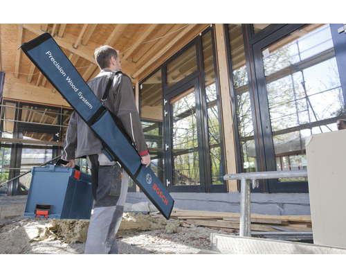 Mann trägt Werkzeugkoffer und Tasche mit Präzisions-Holzbearbeitungssystem vor einem Haus mit Fenstern