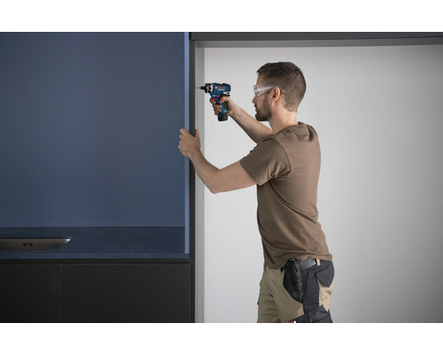 Ein Mann montiert eine Küchenfront mit einem Akkuschrauber.
