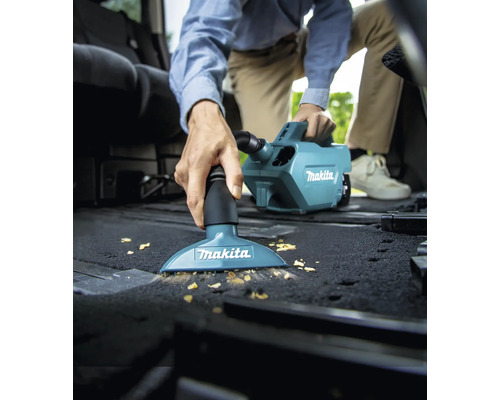 Eine Person saugt mit einem Makita Staubsauger den Innenraum eines Autos