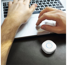 Person arbeitet am Laptop mit einem Smart Home Gerät auf dem Tisch