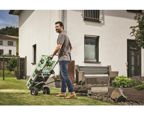 Mann transportiert Getränkekisten mit einer Sackkarre im Garten.