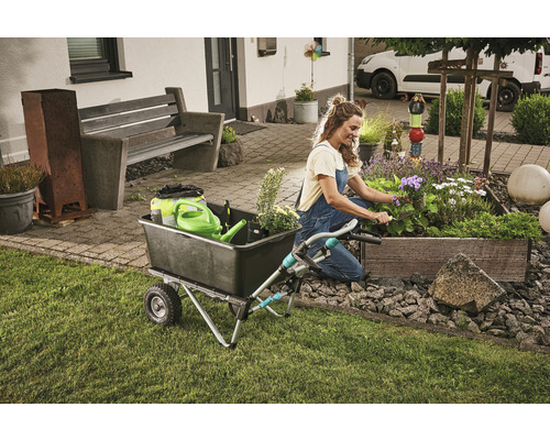 Frau arbeitet im Garten mit einer Schubkarre und einem Pflanzkasten