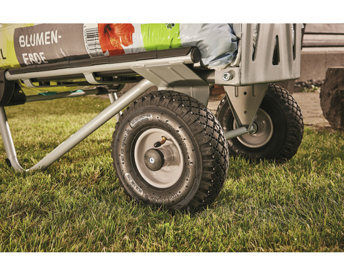 Detailansicht eines Transportwagens mit Blumenerde auf einer Rasenfläche.