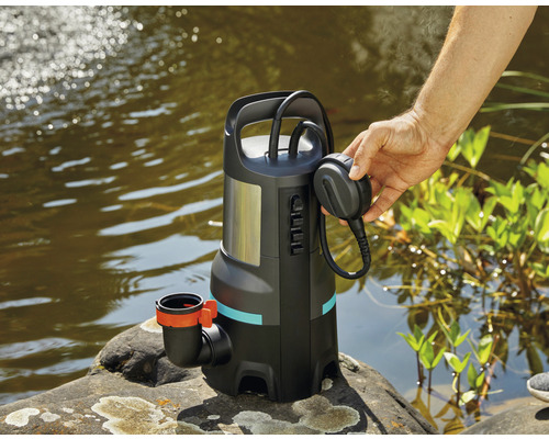 Tauchpumpe am Seeufer mit Stecker in der Hand