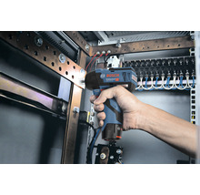 Hand hält einen Bosch Akku-Drehschlagschrauber vor einem Schaltschrank.