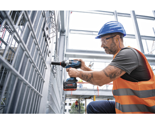 Ein Arbeiter mit einem Akku-Drehschlagschrauber bei der Montage von Metallteilen auf einer Baustelle
