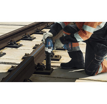 Ein Arbeiter befestigt eine Bahnschiene mit einem Akku-Drehschlagschrauber.