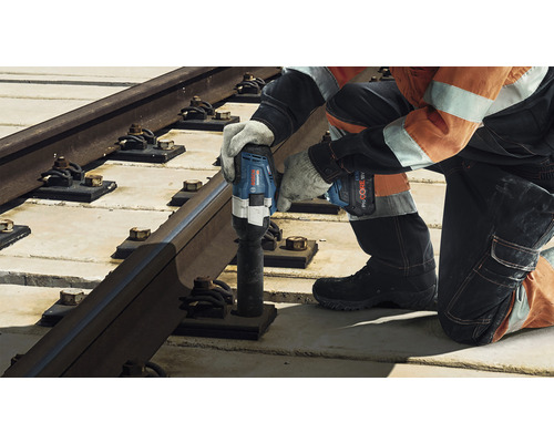 Ein Arbeiter befestigt eine Bahnschiene mit einem Akku-Drehschlagschrauber.