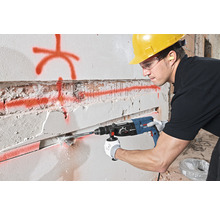 Ein Mann bohrt mit einem Bohrhammer ein Loch in eine Wand.