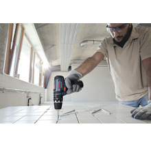 Handwerker bohrt mit Akku-Bohrschrauber Löcher in Fliesen