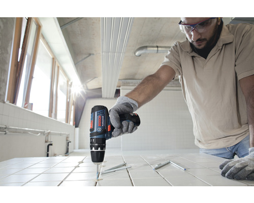 Handwerker bohrt mit Akku-Bohrschrauber Löcher in Fliesen