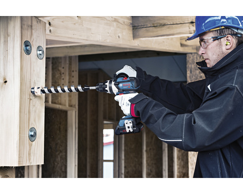 Handwerker bohrt Loch mit einem Akku-Bohrhammer in ein Holzbrett