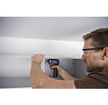 Mann montiert mit einem Akku-Bohrschrauber einen Schrank.