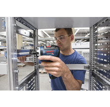 Ein Mann befestigt mit einem Akku-Bohrschrauber eine Metallschiene.