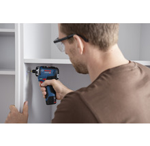 Mann schraubt mit einem Akku-Bohrschrauber ein Regal zusammen