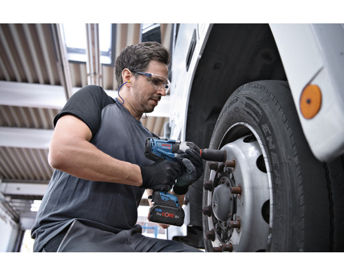 Ein Mann benutzt einen Akku-Schlagschrauber, um ein Rad an einem Fahrzeug zu befestigen.