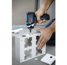 Eine Person bohrt mit einem Akku-Bohrschrauber ein Loch in ein Metallgehäuse.