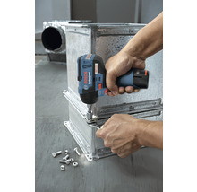 Eine Person befestigt mit einem Akku-Schlagschrauber Metallteile. Schrauben und Muttern liegen daneben.