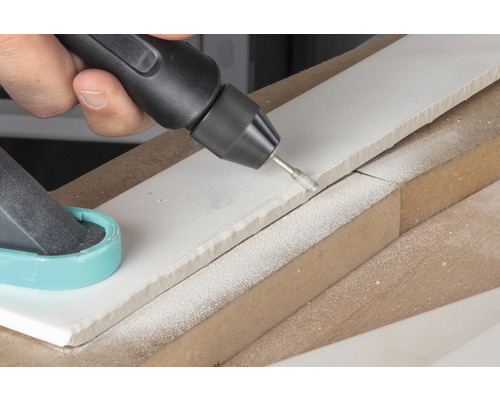 Handwerker bearbeitet Fliesen mit einem Multifunktionswerkzeug