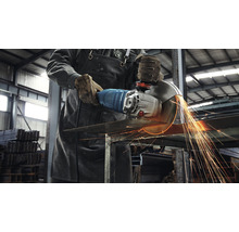 Ein Mann schneidet Metall mit einem Winkelschleifer, wobei Funken fliegen.