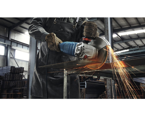 Ein Mann schneidet Metall mit einem Winkelschleifer, wobei Funken fliegen.