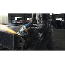 Eine Person schleift Metall mit einem Winkelschleifer, Funken fliegen.