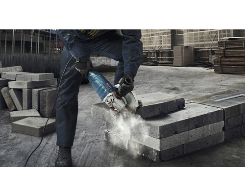 Ein Mann schneidet mit einem Winkelschleifer einen Betonstein.