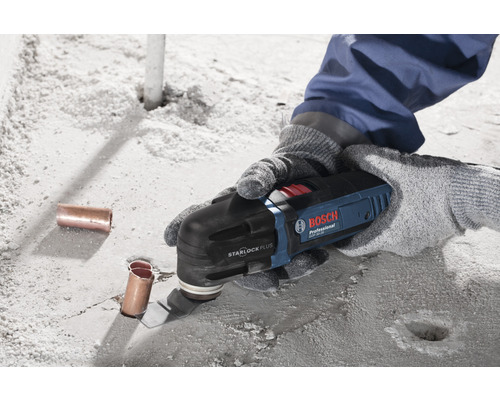 Person benutzt ein Bosch Multifunktionswerkzeug zum Schneiden eines Rohres auf einer Betonoberfläche