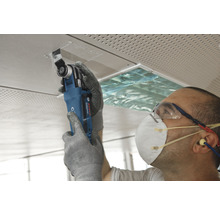 Mann schneidet Deckenplatte mit Multifunktionswerkzeug