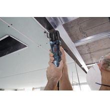 Mann arbeitet mit einem Multifunktionswerkzeug an einer Decke mit Gipskartonplatten.