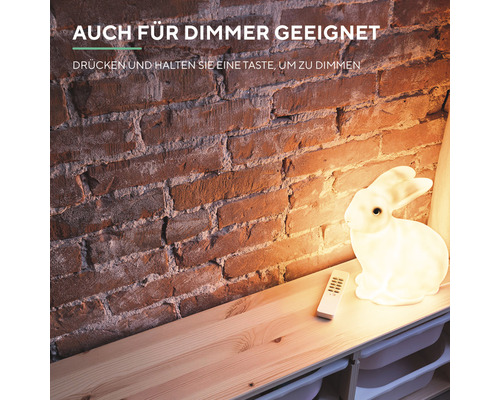 Dekorative Hasenlampe mit Fernbedienung auf einem Holzregal vor einer Backsteinmauer