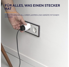 Eine Hand steckt einen Stecker in eine Steckdose an einer Wand
