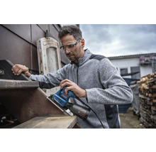 Mann schleift Holztreppe mit einem Schwingschleifer von Bosch