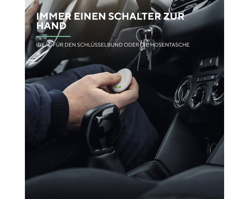 Person im Auto hält einen kleinen runden Funkschalter in der Hand