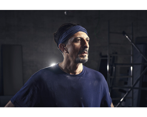 Handwerker mit Stirnband und Arbeitskleidung.