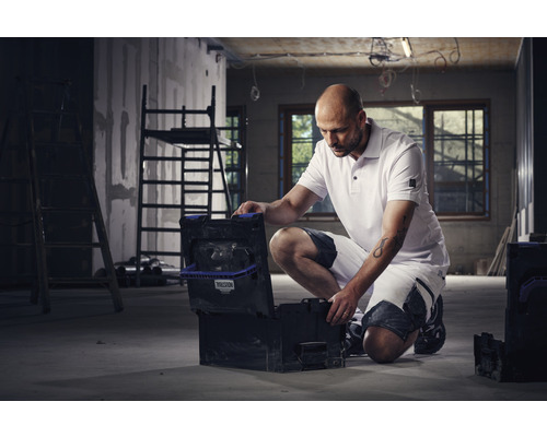 Handwerker mit geöffnetem Werkzeugkoffer in einer Baustelle