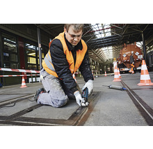 Handwerker bei der Arbeit mit einem Multifunktionswerkzeug in einer Werkshalle
